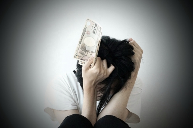お金を手に頭を抱える。箕面市で債務整理の無料相談が司法書士に可能